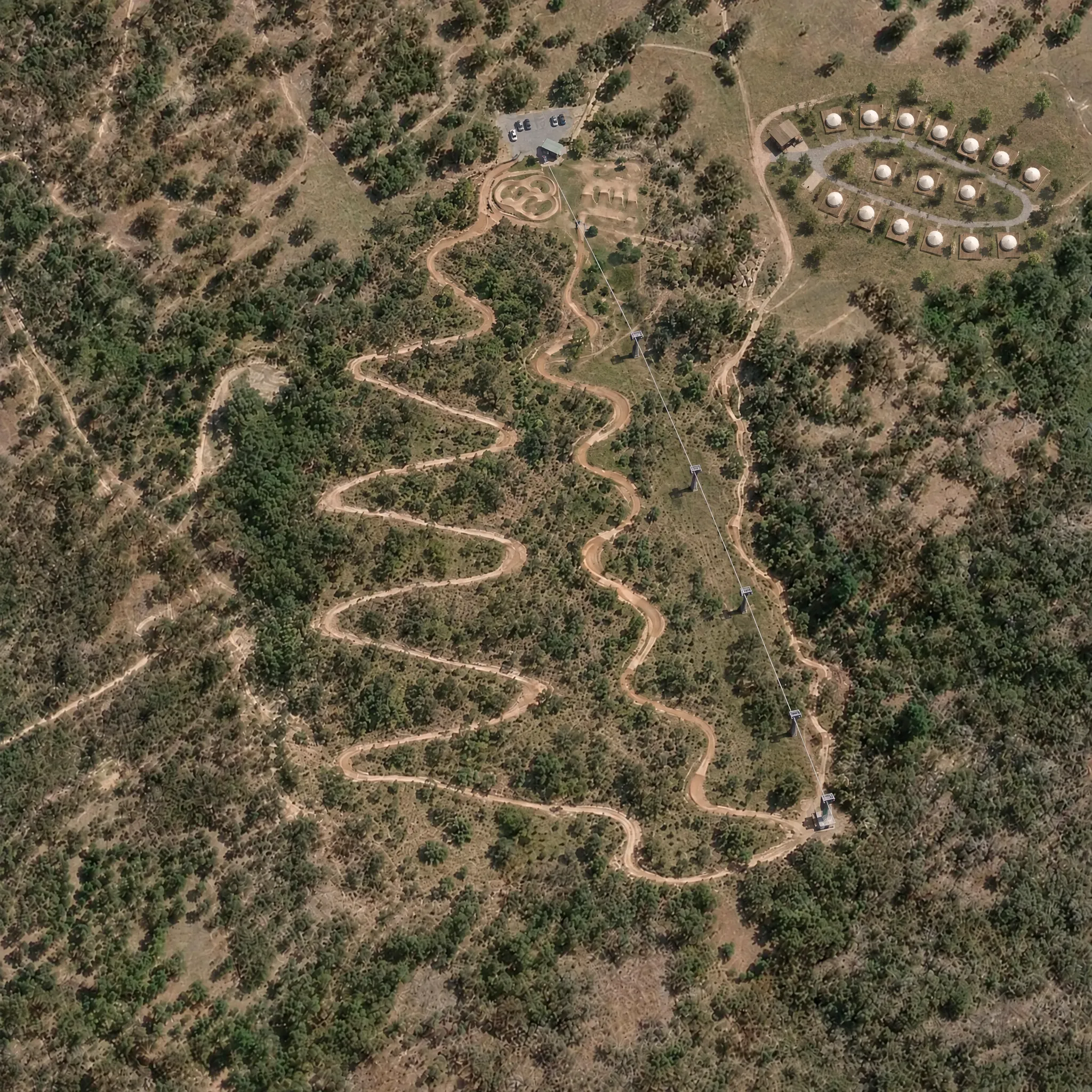 Concept aerial of the planned bike park on the former quarry: three downhill runs, a pulley lift, a kids’ jump park and a glamping camp
